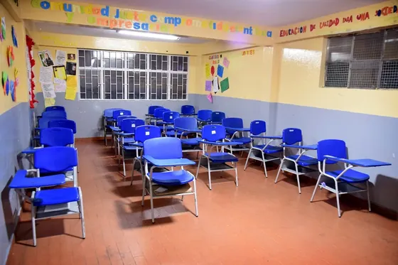 Aula de bachillerato con el lema institucional en la pared
