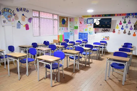 Aula de primaria con pupitres y cartelera de horarios