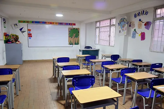 Aula de primaria con tablero y pupitres